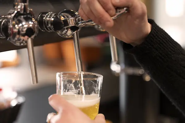 Une personne rempli un verre à bière avec de la bière pression