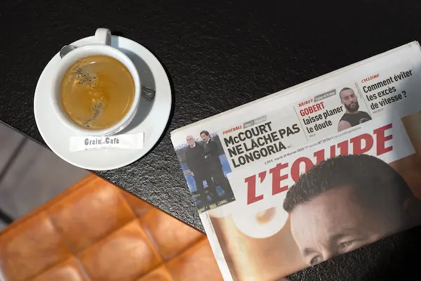 Magazine L'Equipe et un café posé sur une table