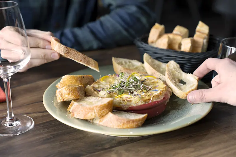 Une assiette de camembert fondu dégustée par 2 personnes avec du pain