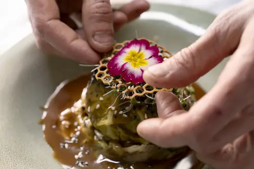 Une personne dépose une fleur sur un plat dressé dans une assiette