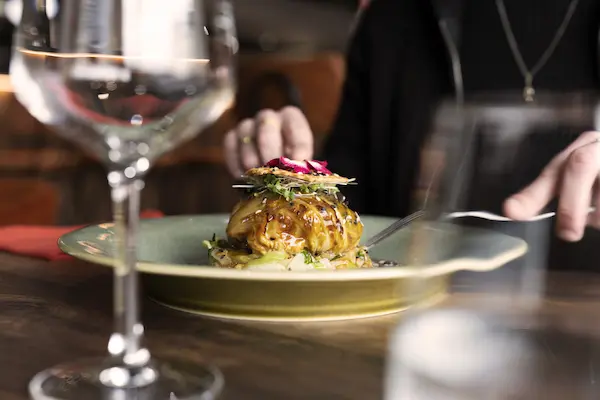 Une personne mange un plat dressé dans une assiette verte